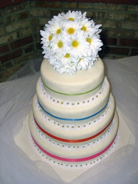 four tier wedding cake with daisy flower as topper