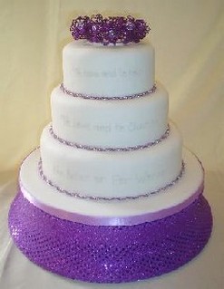 Picture of wedding vows cake with bright purple and white with purple flowers topper