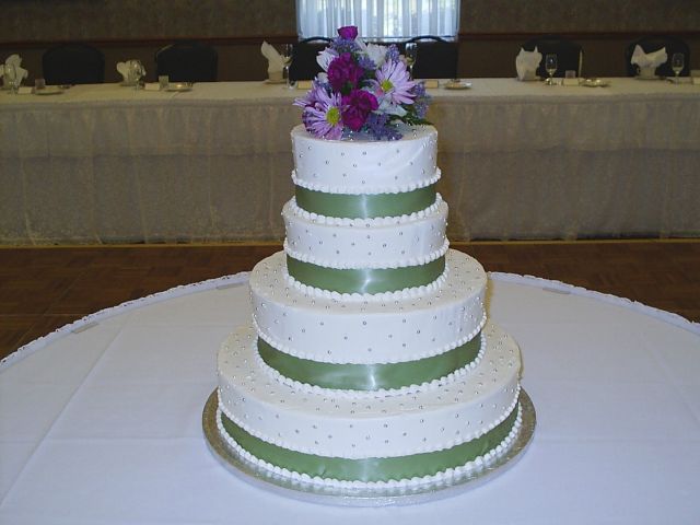 Wedding Cakes in four tier with green ribbons and purple flowers topper
