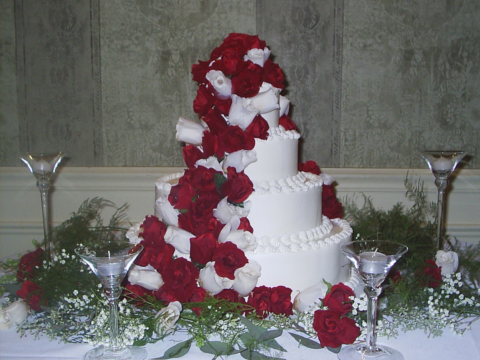 Four white Wedding Cakes with lots of bright red flowers