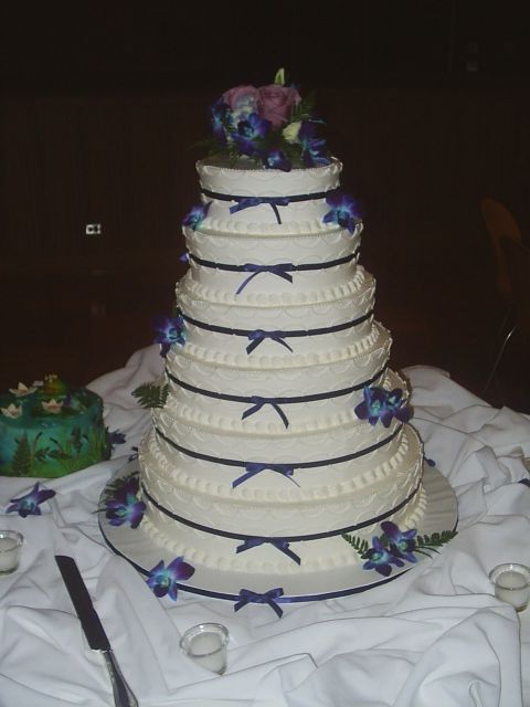 Six tier Wedding Cakes with dark blue and purple floral toper and dark ribbons