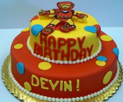 Two tier cartoon robot theme birthday cake in orange and yellow.JPG