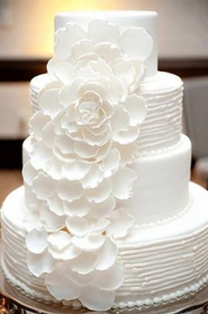 Bright white 4 tier round wedding cake with cascading white flower petals.JPG