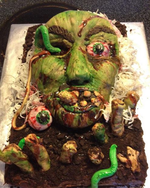 Zombie theme cake with zombie head eyes pupping out and zombie fingers.JPG