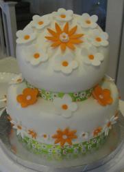 Two tier topsy turvy round white cake with orange and white flowers.JPG