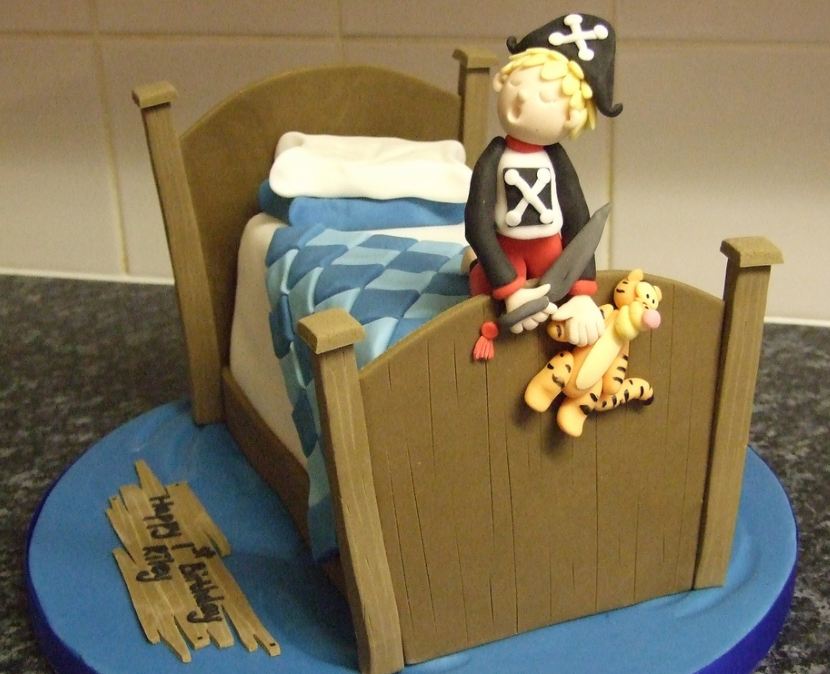 Kid in pirate costume on bed cake.JPG