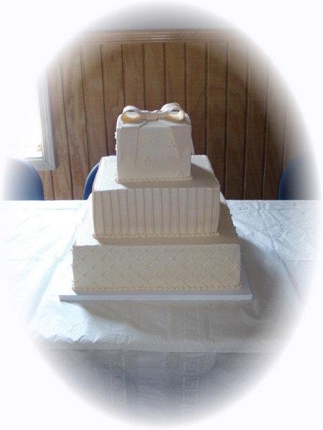 creamy square wedding cake with bow top
