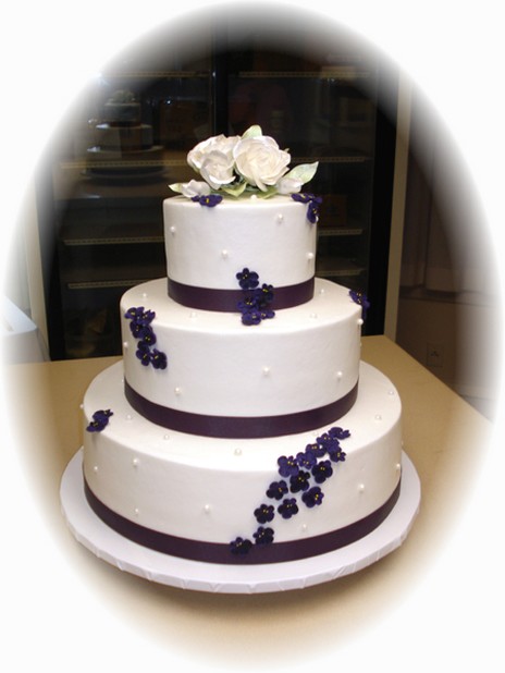gallery of wedding cake with purple ribons and white flowers