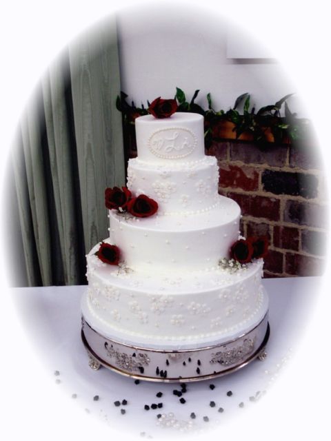 white wedding cake with dark red flowers