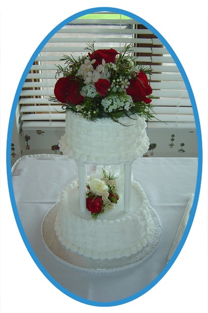 two tier white wedding cake with red roses and white flowers