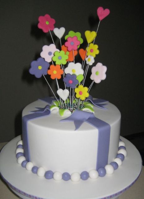 Round white cake with fondant flowers popping out of the middle.JPG