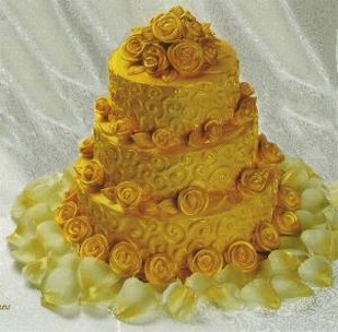 fancy wedding cake in yellow with fresh flowers and glace flowers