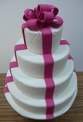Four tier round wedding cake with fuschia bow.JPG