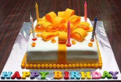 White birthday cake with large orange ribbon and Happy Birthday letters in various colors.JPG