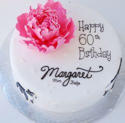 Round white 60th birthday cake with pink flower and cursive writing.JPG