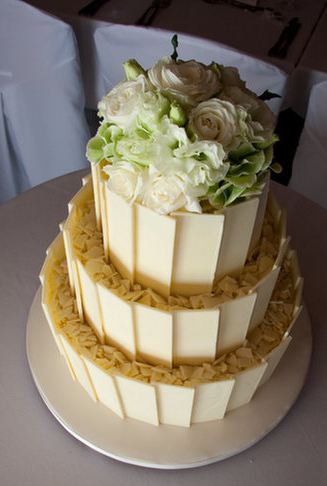 Three tier white chocolate cake topped with white roses.JPG