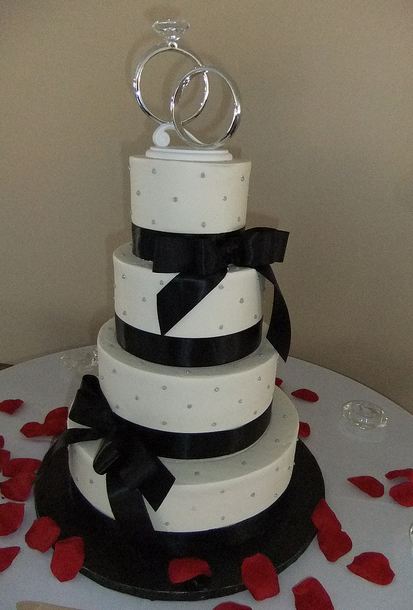 4 tier white round wedding cake with black bows and diamond and wedding ring toppers.JPG