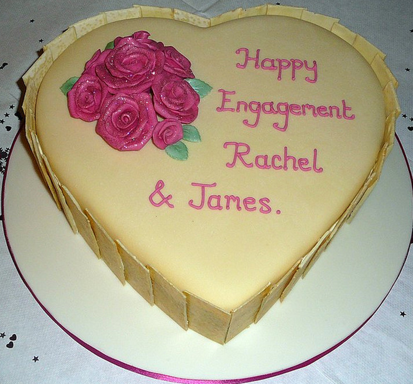 White chocolate engagement cake in heart shape with pink letters.PNG