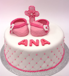 Chic baptism cake in white with pink dots and cross and shoes cake toppers in bright pink.PNG