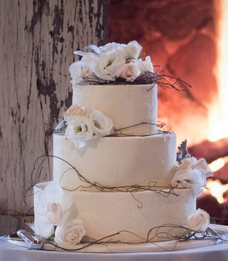 Tri-tier round white wedding cake with white roses and branches.JPG