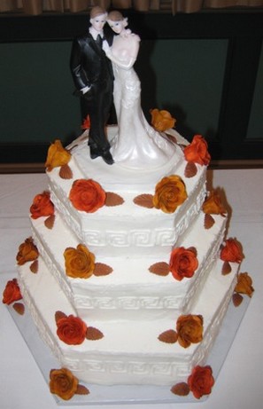 colorful wedding cake with orange flowers and bride and groom topper