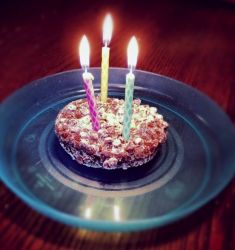 Small chocolate birthday cake with crunchy top and 3 lit candles.JPG