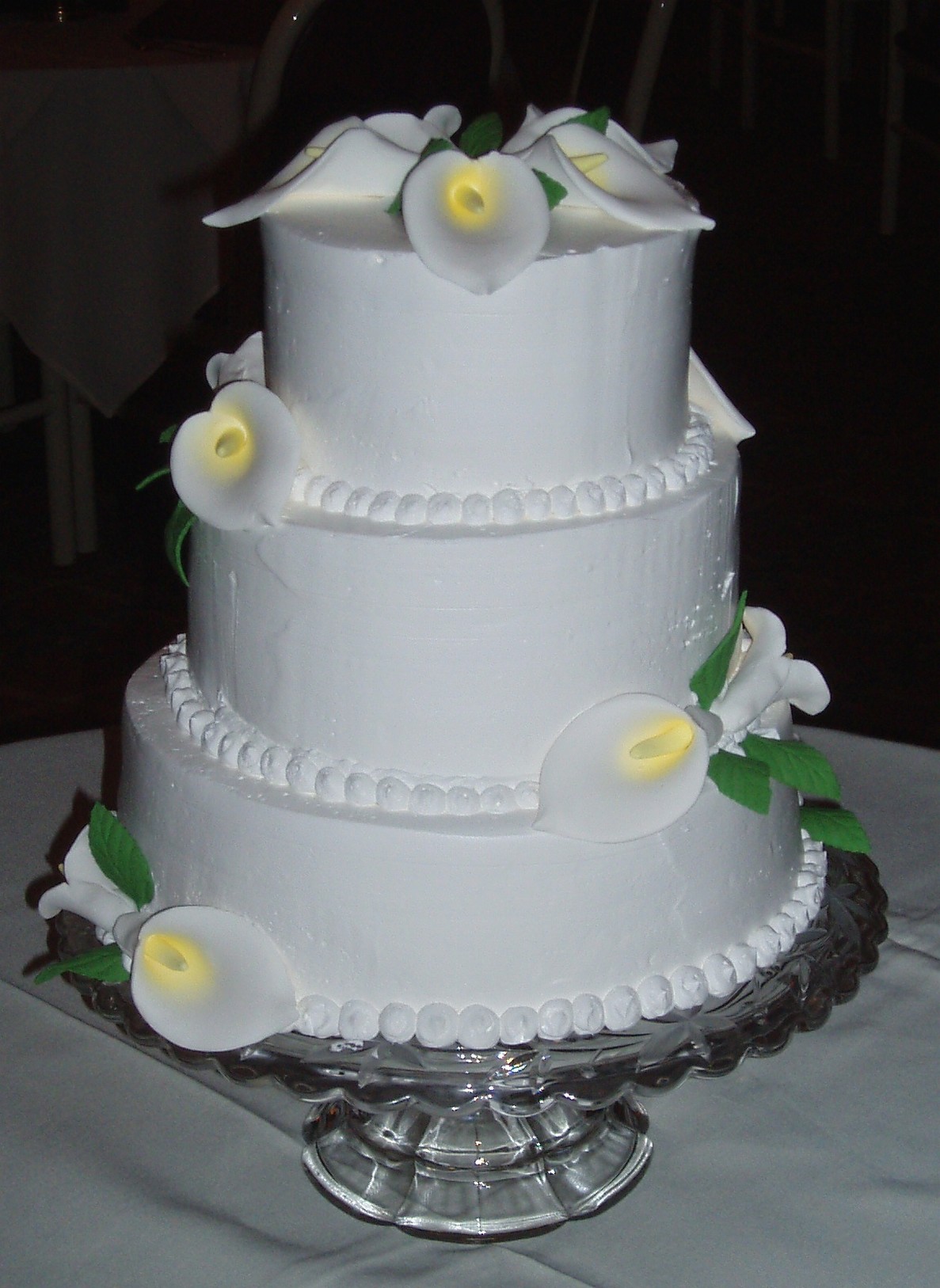 Three tier white wedding cake with lilies flowers