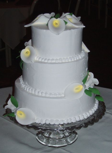 Three tier white wedding cake with lilies flowers