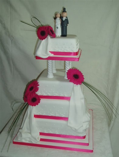 White wedding cake with bright pink ribbons and pink flowers