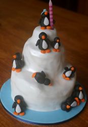3 tier icy mountain Penguin theme cake with single candle on top.JPG