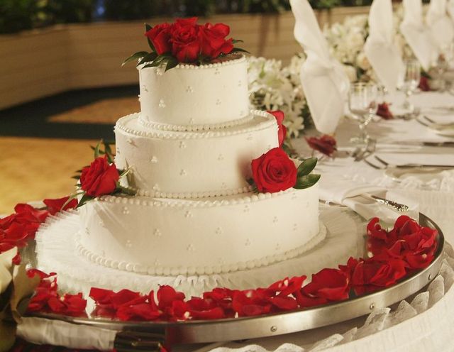 Pretty three tier wedding cake with fresh red roses and petals.JPG